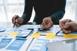 © crizzystudio - ux developers, UI designers Asian group data researchers brainstorm on tabletop mobile app interface wireframe design client summary color codes modern office Creative Digital Development Agency.