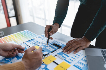 ux developers, UI designers Asian group data researchers brainstorm on tabletop mobile app interface wireframe design client summary color codes modern office Creative Digital Development Agency.