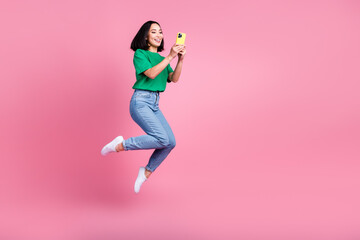 Full body photo of japanese jumping air carefree korean girl hold smartphone fast speed wireless internet connection isolated pink color background