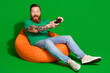 © deagreez - Full length photo of funky cool guy dressed t-shirt sitting bean bag enjoying playstation empty space isolated green color background