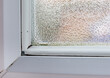 Condensation gathers in the corner of a double glazed window after cold night which can cause mold and health issues