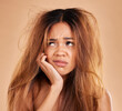 © Lune/peopleimages.com - Sad face, hair loss and woman in studio isolated on a brown background for thinking. Idea, keratin damage or angry female model with haircare, messy hairstyle or split ends after salon treatment fail