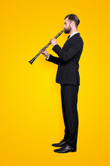 Sticker - Side view half face, full size fullbody portrait of stylish talented musician with hairstyle in black tux with bow, pants, playing on bassoon, isolated on grey background