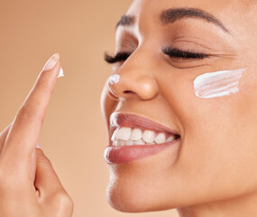 Wall Mural - Face, skincare smile and woman with cream in studio isolated on a brown background. Dermatology, beauty cosmetics and closeup of happy female model with lotion, creme or moisturizer for skin health.