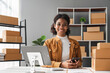 © Natee Meepian - sme business idea. African Americans woman selling online at home with laptop to take orders and to deliver yellow parcel boxes online delivery ideas