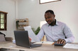 © Natee Meepian - Focused african businessman holding documents looking at laptop doing research. business financial analyst concept