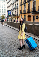 Wall Mural - A tourist girl walking around with her suitcase looking for tourist flats