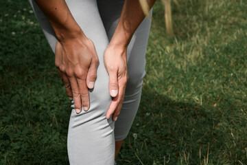 Uraz kolana. Młoda kobieta podczas treningu fitness w parku cierpi z powodu bólu kolana. Knee injury.  A young woman suffers from knee pain during fitness training in the park.