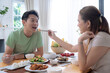 © Basicdog - Happy Asian family enjoying lunch together at home.