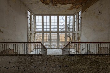 Canvas Print - Closeup of two-barred iron rails in an abandoned building with windows in it