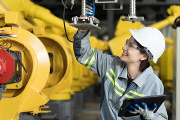 Automated manufacturing industries. Female engineer checking, repair, maintenance autonomous robotics arm for manufacturing lines in workshop. Innovative technology concept