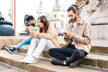 Side View Of Diverse Guys And Girls Using Smartphone Device - People Addicted By Mobile Phone - Tech Life Style Concept With Always Connected Students - Bright Filter With Focus On First Right Man