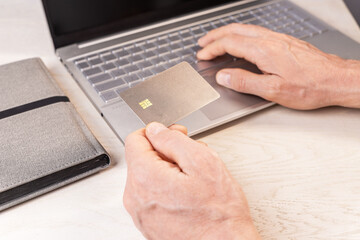 Poster - Hand holding bank credit card mock-up, bankcard mockup with chip at workplace, entering data for online payment with laptop keyboard