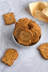 Wall Mural - Funny baby cookies in the shape of animals in a gray ceramic bowl on a gray marble table with  a yellow napkin next to it. Baby food. Baking for children.