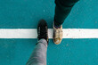 Two people foot standing on a white line on the ground. Border crossing