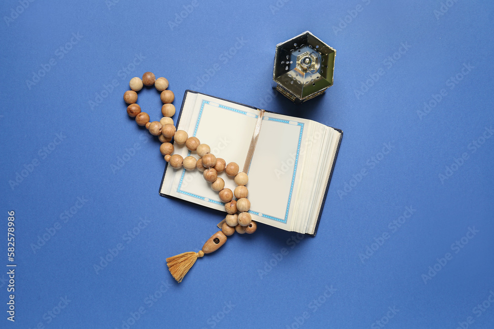 Koran with prayer beads and Muslim lantern for Ramadan on blue background