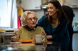 © Studio Dva Kera - Senior woman and nurse enjoying a nutritious meal together at a dining table in a retirement home.