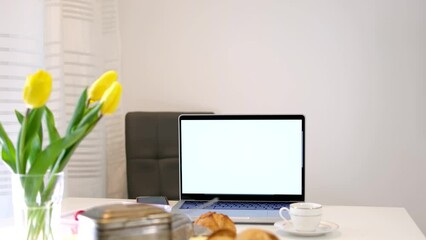 on table breakfast Yellow tulips laptop with a white screen for advertising buns a cup of coffee or tea on a white background space for text beauty Tenderness home comfort