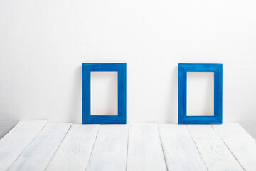 two empty blue picture frames on white wooden table