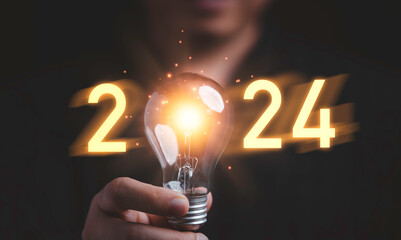 Wall Mural - Businessman holding glowing lightbulb with 2024 number for creative thinking idea for start new business concept.