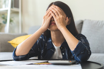 Wall Mural - Business financial concept, owe asian young woman, female sitting cover face with hands, stressed by calculate expense from invoice or bill, have no money to pay mortgage or loan. Debt, bankruptcy.