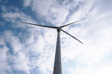 Wall Mural - Wind generator turbine against blue cloudy sky.