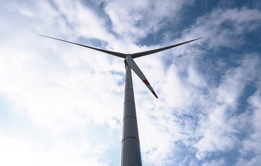 Wall Mural - Wind generator turbine against blue cloudy sky.