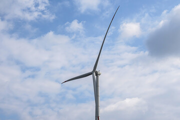 Wall Mural - Wind generator turbine against blue cloudy sky.