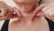 close up the fingers holding the flabbiness adipose hanging skin, wrinkle and Inflammation skin under the neck, wattle and cellulite under the chin of the woman, health care and beauty concept.