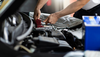 Wall Mural - Auto mechanic worker checking and changing car battery. Car maintenance and auto service garage concept.