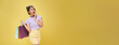 © NaMong Productions - Cheerful happy thai asian woman enjoying shopping, she is carrying shopping bags isolated on copy space yellow background