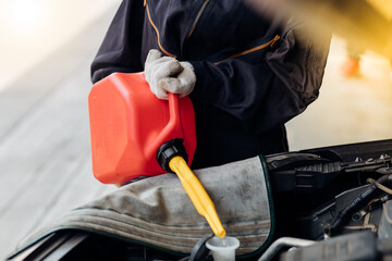 Wall Mural - Hispanic mechanic woman filling water to car radiator. Auto mechanic working in garage