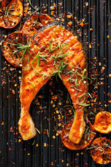 Wall Mural - Grilled salmon steak in tangerine marinade with herbs and spices on a grill plate, top view