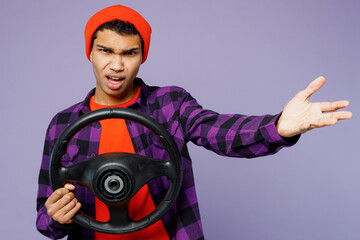 Wall Mural - Young mad angry outraged man of African American ethnicity wears casual shirt orange hat hold steering wheel driving car spread hand isolated on plain pastel purple color background studio portrait.