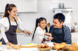 © Art_Photo - Portrait of enjoy happy love asian family father and mother with little asian girl daughter child play and having fun cooking food together with baking cookie and cake ingredient in kitchen