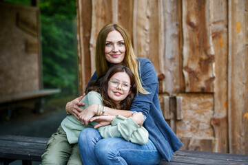 Portrait of little school girl with glasses and mother hugging together. Cute daughter and happy woman. family, childhood, happiness and people