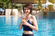 © ALEXEY - Sportswoman drinks a cocktail of fresh fruits near the pool.