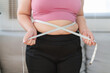 © mojo_cp - Close up overweight woman measuring her hip with tape measure..