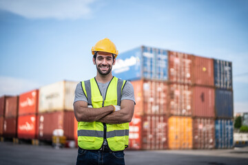 Caucasian warehouse worker in uniform with hard hat standing in container port terminal. Area logistics import export and shipping.