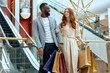 © Roman - young joyful couple in stylish bussiness clothes, outfit enjoying shoppping time at weekend, holiday day off, enjoyment.escalator in the background of the photo