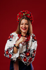 Wall Mural - Portrait of ukrainian woman in traditional ethnic clothing and floral red wreath on viva magenta studio background. Ukrainian national embroidered dress call vyshyvanka. Pray for Ukraine