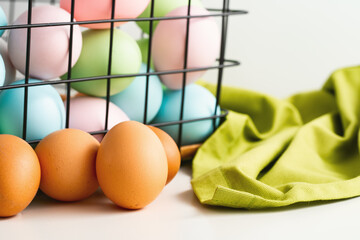 Wall Mural - Many dyed Easter eggs in metal basket. Several natural brown eggs in front of it. Easter holiday eggs hunt and painting concept.