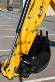 Fototapeta  - construction bucket of tractor, excavator or industrial machine. Yellow hydraulic arm with black ladle