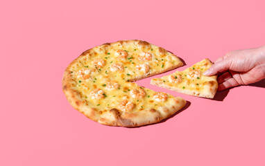 Wall Mural - Eating shrimp pizza, minimalist on a pink background. Taking a slice of pizza