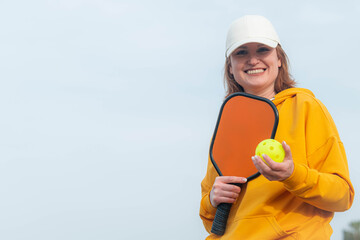 portrait woman player pickleball game over blue sky, pickleball yellow ball with paddle, outdoor sport leisure activity