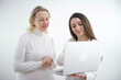 © Oleksandra - young girl doctor shows tests on laptop to an adult woman in white clothes on a white background advertising a good medicine helping patients care internet consultation online hospital polyclinic