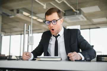 Wall Mural - Angry senior businessman sitting at his desk and screaming