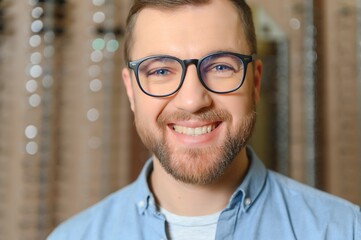 Man is choosing glasses in optics store.