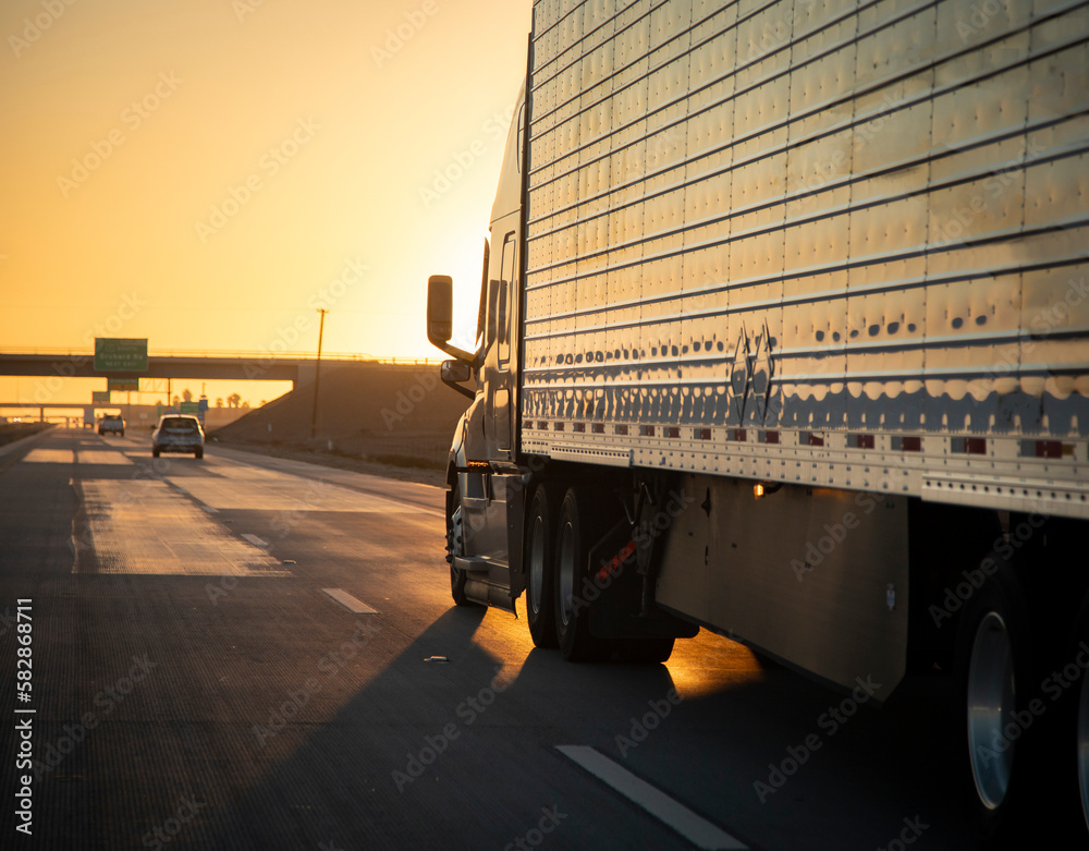 Long Haul 18 Wheel Truck driving on a highway at sunrise or sunset ...