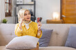 © David - Portrait of smiling Asian young Muslim woman in hijab head scarf at home and holding credit card against Easy payments paying for utilities.